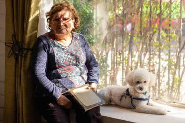 Evde bir köpeğin yanında oturan kızgın bir büyükanne.