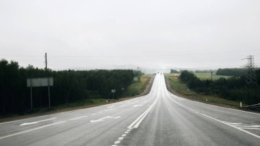 Murmansk region - August 2018: Panoramic view of the misty asphalt road in rainy weather. Foggy winding highway surrounded by mountains and hills in Kola Peninsula. Summer morning road and fog.