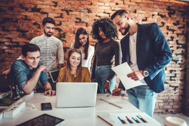 Bir grup iş adamı birlikte çalışıyor. Modern bir ofiste dizüstü bilgisayarın önünde oturan genç iş adamları.