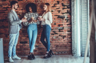 İş, ara, iletişim ve insanlar konsepti - mutlu yaratıcı takım kahve içiyor ve ofiste konuşuyor