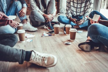 Ofisteki kahve molası sırasında yerde birlikte oturan ve kafasız ateş eden bir grup genç iş arkadaşı.