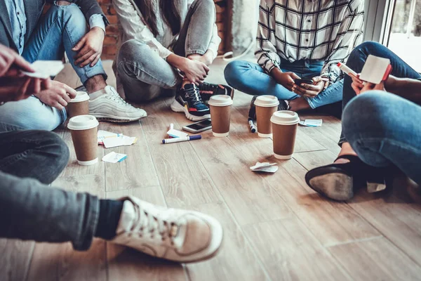 Ofisteki kahve molası sırasında yerde birlikte oturan ve kafasız ateş eden bir grup genç iş arkadaşı.