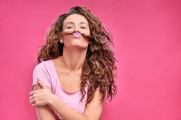 Photo of amazing lady sending air kisses pretending like man making false moustache with curl wear casual isolated pink background. Copy space