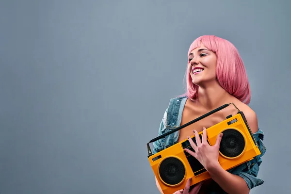 Old-school people person glamour leisure lifestyle concept. Studio photo portrait of beautiful pink hair girl holding tape cassette radio isolated grey background. Copy space