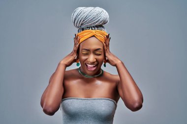 Gri arka plan yüzünden sinirli ve kızgın bir Afrikalı kadın. Ön görünüm