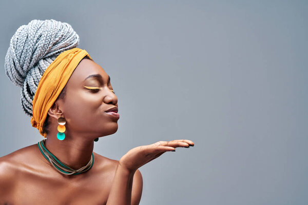 Side view of young african american girl posing isolated on grey background in studio. People sincere emotions lifestyle concept. Copy space. Blowing sending air kiss