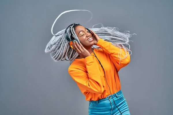 Afro american woman portrait with big afro braids on gray background dancing and with hairstyle flying in air. Copy space