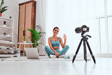 Tripod kameralı genç blogcu evde online fitness sınıfını kaydediyor. Uzayı kopyala Düşük açılı çekim