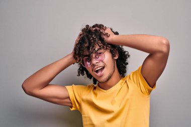 Havalı, genç, heyecanlı, kıvırcık saçlarını toplayan, gülümseyen kamerasını takan doğu çocuğu. Süslü pembe gözlüklü Arap yakışıklı adam.