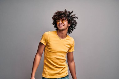 Gri arka planda sarı gözlüklü yakışıklı ve sıradan kıyafetler giyiyordu. Gülümseyen kıvırcık Arap tarzı öğrenci