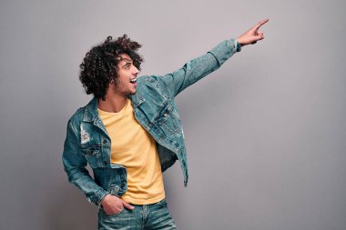 Gri izole arka planda fotokopi alanını gösteren heyecanlı genç adamın yan görüntüsü. Reklam, indirim, satış, sansasyon konsepti