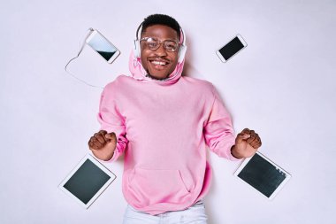 Bir sürü ekranı, cep telefonu ve tabletleri olan genç afro adam. Çok fazla iletişim konsepti. İnternet sosyal medyası. Üst görünüm