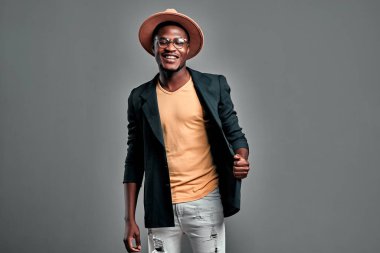 Şapkalı yakışıklı, sakallı afro adamın portresi gri arka planda soyutlanmış. Boşluğu kopyala