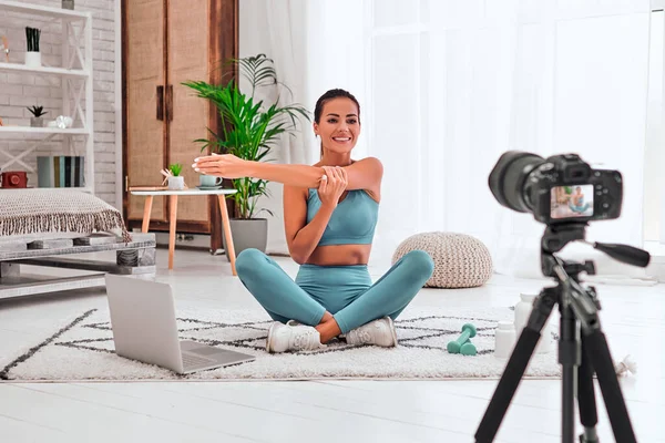 Fitness woman blogger recording video on camera, training home in living room. Concept Lifestyle influencer sport and recreation.