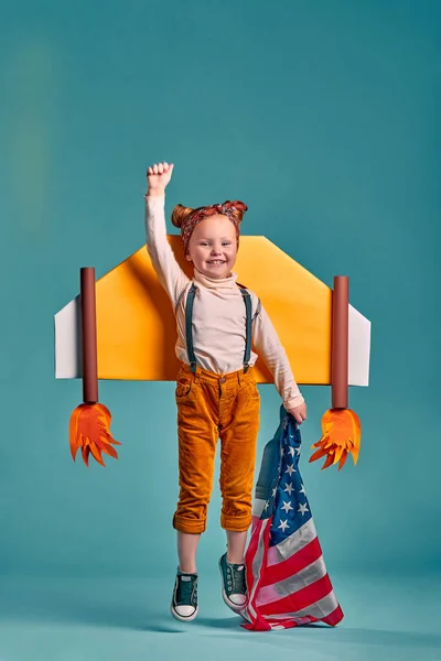 Little girl and American flag, isolated on blue background. Vertical photo