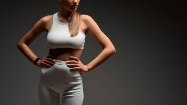 Gri arka planda spor kıyafetleriyle poz veren kaslı genç bir kadın görüntüsü. Stüdyoda mükemmel gövdesi olan uygun bir kadın model. Web afişi. Boşluğu kopyala.
