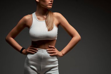 Elleri belinde olan sağlıklı bir kadının gövdesinin yakın görüntüsü. Gri arka planda mükemmel karın kasları olan bir kadın. Kesilen resim.