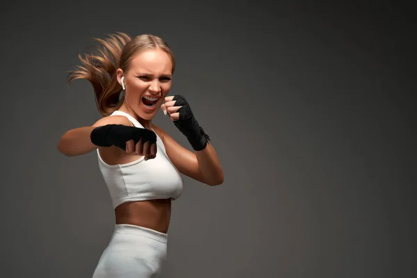 Portrait of a female mixed martial arts fighter with a bandage on her hands. Isolated grey background. Copy space.