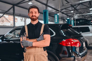 Atölyedeki gülümseyen araba tamircisi. Araba servisi, onarım, bakım ve insan konsepti. Ön görünüm.