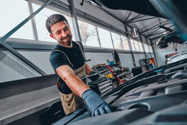 Elinde dosya olan tamirci garajdaki arabayı kontrol ediyor. Seçici odak.