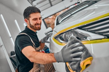 Üniformalı oto hizmet görevlileri mikrofiber bezle araba temizliyor. Araba temizliği ve vale konseptleri. Seçici odaklanma. Görüntüyü kapat.