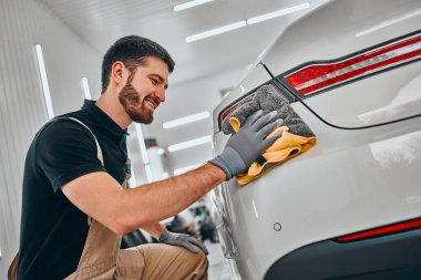 Erkek işçi otomobili paçavrayla temizliyor. Araba yıkama ve araba yıkama konsepti. Görüntüyü kapat.