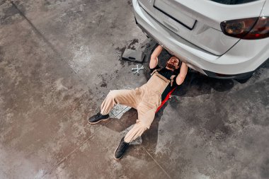 Yerde yatıyordu. Üniformalı eleman otomobil salonunda çalışıyor. Yüksek açı. Boşluğu kopyala.
