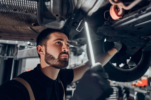 Mecánico Inspeccionando Coche Levantado Vista Cerca Enfoque Selectivo —  Fotos de Stock