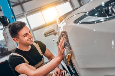 Araba tamiri. Adam mikrofiberi elinde tutuyor ve arabayı cilalıyor. Seçici odak.