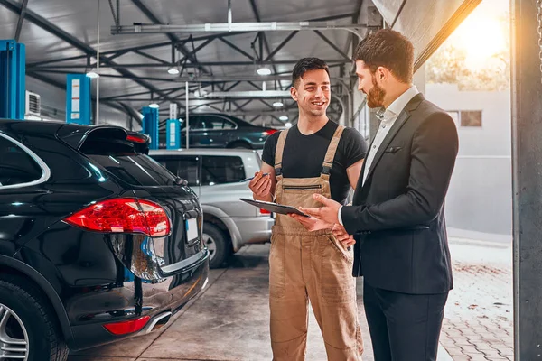 Giovane Meccanico Cliente Uomo Guardando Gli Appunti Sorridendo Garage — Foto Stock