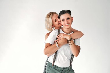 Cheerful lesbians embrace passionately and have fun together. Isolated white background. Copy space.