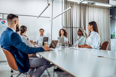 İşine odaklan. Genç iş adamları birlikte çok güzel bir ofiste çalışıyorlar. Bir grup genç iş adamı iş yerinde iş arkadaşlarıyla birlikte çalışırken ve iletişim kurarken..