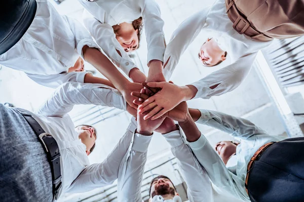 Young business people. The concept of unity and teamwork. Men and women joined in a circle with their hands together in a huddle to start working on an important project. Bottom view.