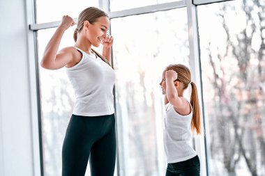 Anne ve kızı jimnastik salonunda güçlü eller gösteriyor. Sportif aile kavramı