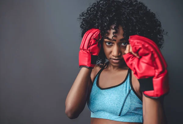お前を倒す 戦闘姿勢で美しいアフリカの女性のボクサーの肖像画 女の子で赤ボクシング手袋上の灰色の背景 — ストック写真