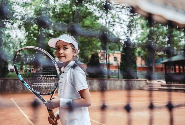 スポーツクラブでテニスラケットを持つ女の子 屋外でテニスをしているラケットを持ったスポーティーな女の子のトリミングされたイメージ テニスコートの子供アスリート 幼い子供のための訓練 — ストック写真