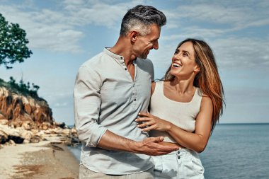 Attractive couple walking and embracing on the beach on a sunny day.