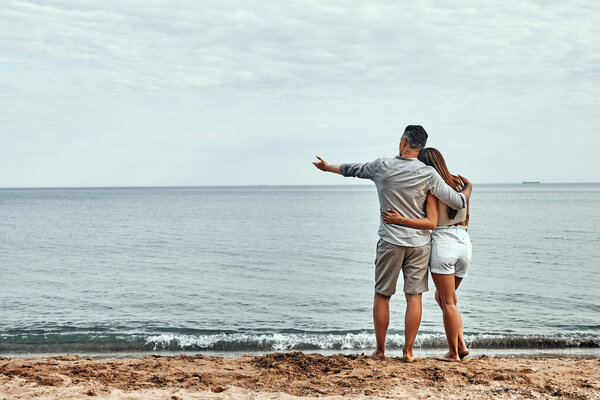 Beach couple walking on romantic travel honeymoon vacation summer holidays romance. Back view of casual happy lovers in full body length on beach. Copy space