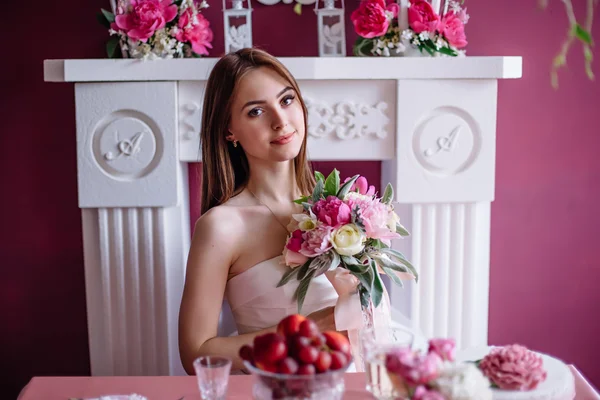 Jonge mooie bruid met een boeket van roze pioen in de buurt van de witte open haard — Stockfoto
