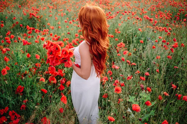 ケシの花の花束を保持にケシ畑で美しい若い赤髪の女 — ストック写真