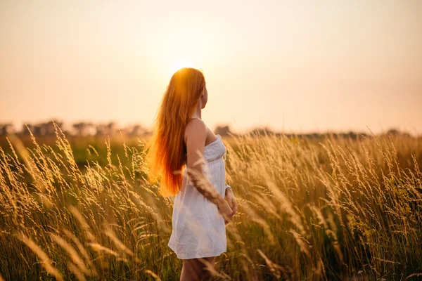 Jovem linda menina ruiva em um campo ao pôr-do-sol — Fotografia de Stock