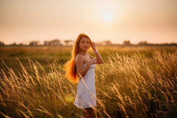 Junge schöne rothaarige Mädchen in einem Feld bei Sonnenuntergang — Stockfoto