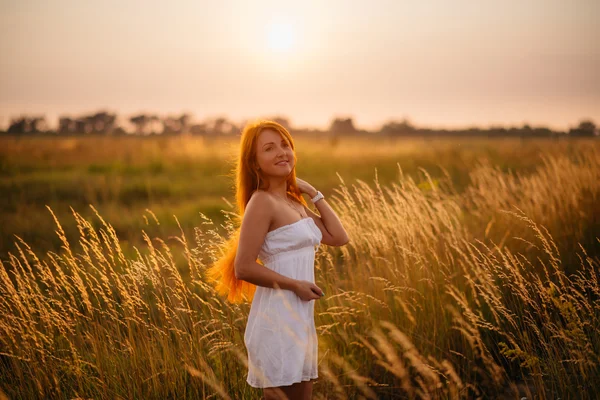 Jovem linda menina ruiva em um campo ao pôr-do-sol — Fotografia de Stock