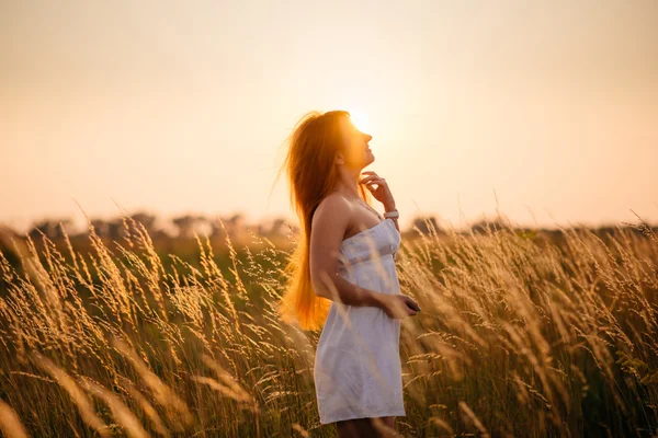 Jovem linda menina ruiva em um campo ao pôr-do-sol — Fotografia de Stock