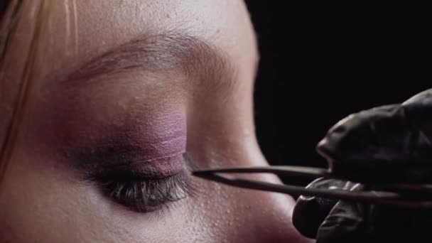 Maquiagem artista estende pestanas. — Vídeo de Stock