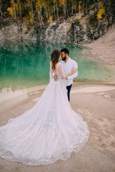 Friss házasok állnak egy gyönyörű tó mellett.. — Stock Fotó