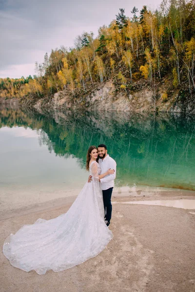 Les jeunes mariés sont debout près d'un beau lac. — Photo