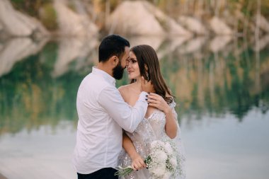 Yeni evliler güzel bir gölün yanında duruyor..