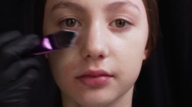 Makyaj sanatçısı müşteriye makyaj yapıyor.