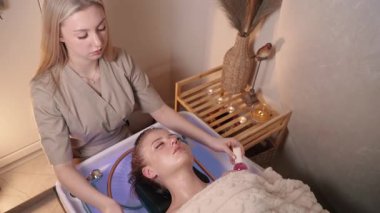 Profesyonel güzellik uzmanı, japon spa salonunda genç bir kadına cam toplarla yüz masajı yapıyor. Yüzünü kapat..